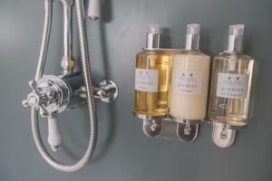 a bathroom with three bottles of soap and a shower at Old Bank Rooms in Bourton on the Water