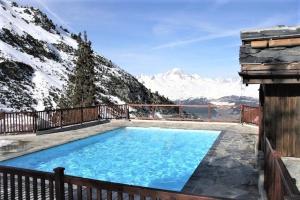 a large swimming pool with snow covered mountains in the background at Appartement montagne spacieux, piscine, SPA à ARC 1950 in Arc 1950