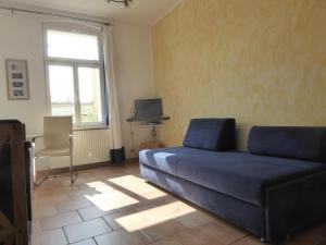 a living room with a blue couch and a window at Villa Mutabor in Ahlbeck