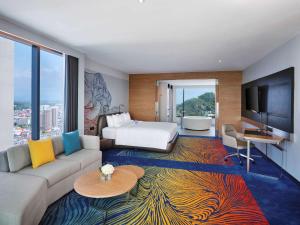 是拉差的住宿－Novotel Marina Sriracha，酒店客房设有沙发、床和电视。