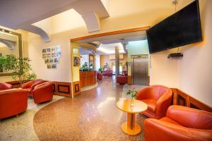 a waiting room with red chairs and a flat screen tv at Hotel Fenix in Jelenia Góra