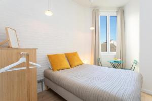 sypialnia z łóżkiem z żółtymi poduszkami i oknem w obiekcie Canela Homes BARCELONA MARINA w Barcelonie