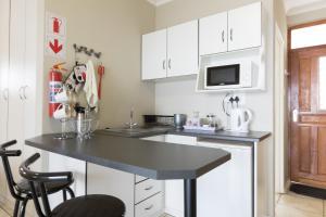 uma cozinha com um balcão preto e armários brancos em View Lodge em Gariepdam