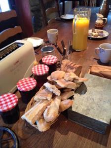 a wooden table with a plate of bread and orange juice at Au Chant Des Marmites in Saint-Lary-Soulan