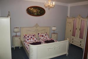 a bedroom with a bed with pink pillows and a chandelier at Hotel Corrado in Ostrava
