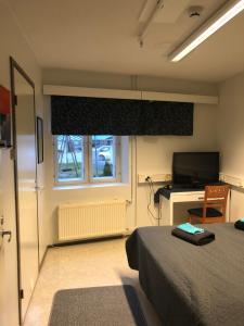 a bedroom with a bed and a television and a window at Hostel400Kokkola Tehtaankatu in Kokkola