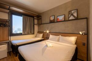 um quarto de hotel com duas camas e uma janela em ibis Ponta Grossa em Ponta Grossa