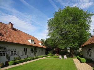 a yard with two white chairs and a tree at de Bosch in Lummen