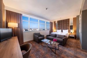 a hotel room with a bed and a couch and a television at Grand Sapphire City Hotel in Famagusta