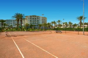 a tennis court in front of a building with palm trees at Iberostar Selection Royal El Mansour in Mahdia