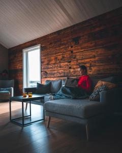 a person sitting on a couch in a living room at Hattvika Lodge in Ballstad