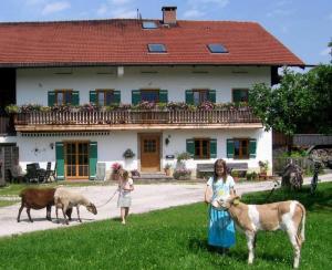 zwei Mädchen stehen vor einem Haus mit Ziegen in der Unterkunft Zaissererhof in Brannenburg