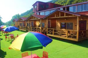 a log cabin with tables and chairs and umbrellas at Oxygen Resorts Mahabaleshwar in Mahabaleshwar