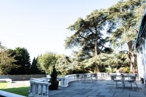 un patio con sillas, mesas y árboles en Manor Parc Hotel, en Cardiff