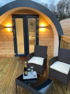 a patio with two chairs and a table with a bottle of wine at Loch Ness Pods in Fort Augustus