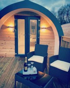 a patio with two chairs and a table with a bottle of wine at Loch Ness Pods in Fort Augustus