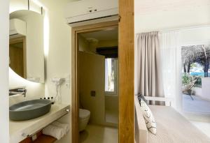 a bathroom with a sink and a toilet and a window at Karidi Beach Boutique Suites in Vourvourou +37 photos