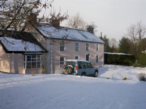 un'auto parcheggiata di fronte a una casa nella neve di Lisnafillan Lodge a Ballymena