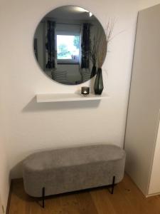 a round mirror on a wall with a ottoman in a room at Ferienwohnung Gasser in Ebringen