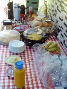 uma mesa com comida e pratos numa toalha de mesa xadrez em Pousada do Chileno na Praia Grande