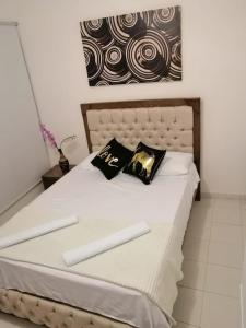 a bed with white sheets and black pillows on it at SAN JACINTO HOSTEL in Cartagena de Indias