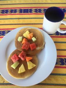 two pancakes with fruit on a plate next to a cup of coffee at Hotel Amigo in Panajachel