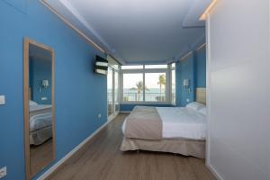 a blue bedroom with a bed and a large window at Luxury Ocean Beach Apartment in Altea
