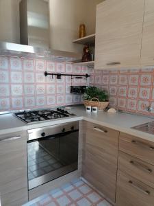 uma cozinha com fogão e azulejos cor-de-rosa em Casa vista Saint Vincent accanto alle Terme em Saint-Vincent