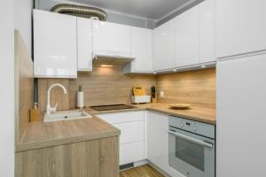 uma cozinha com armários brancos e um lavatório em Apartment Poznan Park Cytadela by Renters em Poznań