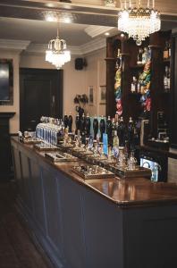 un bar en un restaurante con lámparas de araña y vasos en The Lord Grenfell en Maidenhead