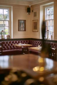 uma sala de jantar com mesas, cadeiras e janelas em The Lord Grenfell em Maidenhead