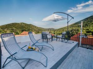 una terraza con sillas, una mesa y una sombrilla en Villa La Vita, en Prgomet