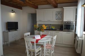 Una cocina con gabinetes blancos y una mesa y sillas. en Le Bozze "Il Leccino" con piscina, WI-FI, posto auto, en Castagneto Carducci