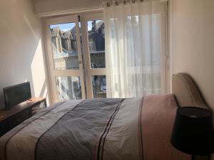 a bedroom with a bed and a large window at Duplex centre ville 200m de la plage in Dinard
