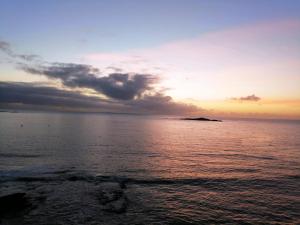 a sunset over the ocean with an island in the distance at Villa bord de mer avec piscine et jacuzzi in Pénestin