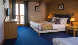 a hotel room with two beds and a television at Chalet Hotel L’Ecrin in Tignes