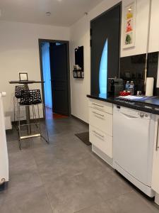 a kitchen with white cabinets and a black counter top at Appartement 2 pièces neuf et indépendant in Jouy-en-Josas