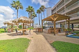 a patio with tables and umbrellas and palm trees at Updated Front Beach Condo w/ Resort Amenities! in Corpus Christi