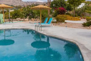 een zwembad met 2 stoelen en een parasol bij CrossRhodes Villas in Pefki Rhodes