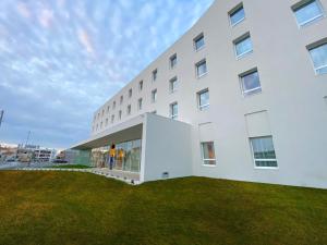 a white building with a grassy yard in front of it at Campanile Caldas da Rainha in Caldas da Rainha