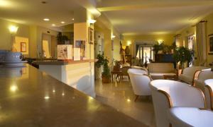 a restaurant with a bar with white chairs and tables at Lion's Hotel in Falerna