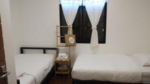 a bedroom with two beds and a window with curtains at Comeneetee Uthai in Ban Khok Mo