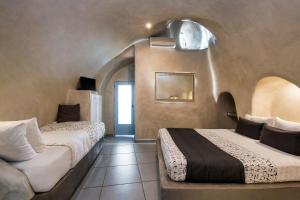 a bedroom with two beds and a chair in a room at Katerina's Castle - Caldera Cave Hotel in Imerovigli