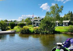 a boat parked in front of a house on a river at Rangeley Town & Lake in Rangeley