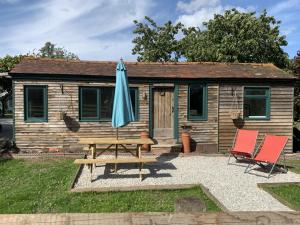 a wooden cabin with a picnic table and an umbrella at Truly Kentish Holiday Lets in Kent