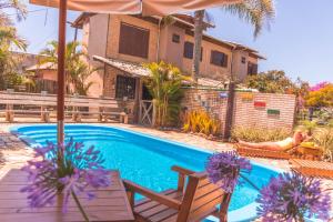 a woman sitting in a chair next to a swimming pool at Pousada Uluwatu, Praia do Rosa in Praia do Rosa