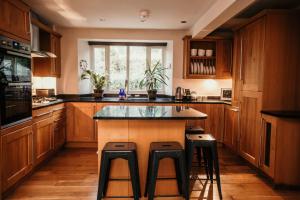 een keuken met houten kasten en een eiland met krukken bij Anchor Cottage Noss Mayo in Plymouth