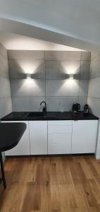 Una cocina con gabinetes blancos, fregadero y luces. en Apartament Vilda, en Poznan 11 fotos más