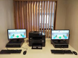 two computer monitors and a printer on a desk at Holiday Inn Express Maspeth, an IHG Hotel in Queens