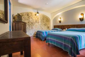 Zimmer mit 3 Betten mit blauer und grüner Bettwäsche in der Unterkunft Posada del Cafeto in Xalapa